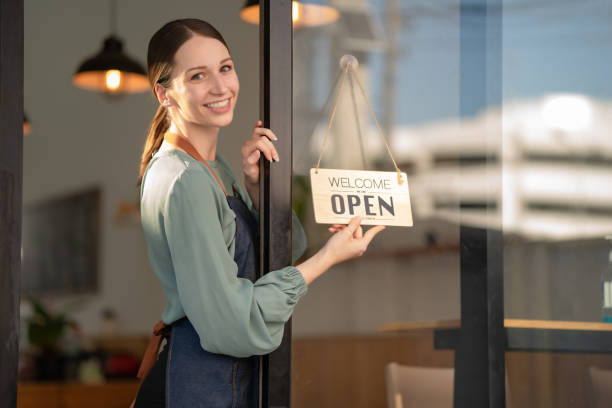 istock A beautiful young coffee shop owner holds an open sign. 1452170020