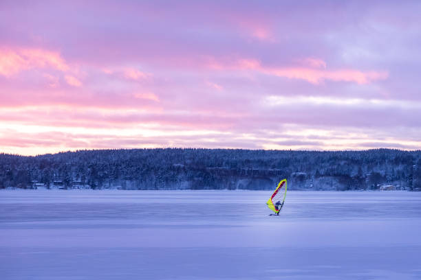 sporty zimowe, mężczyzna jeździ na windsurfingu. jasny zachód słońca nad jeziorem w finlandii. - windsurfing obrazy zdjęcia i obrazy z banku zdjęć