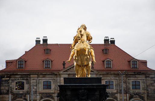 gold statue of european noble warrior knight with historic building in the background