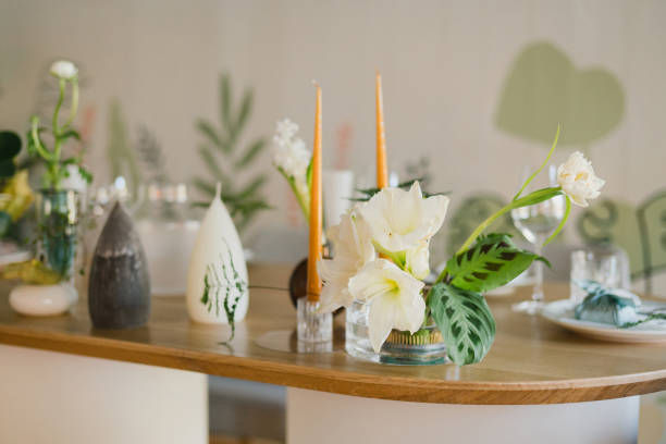 istock Table setting at wedding reception. Floral compositions with beautiful flowers and greenery, candles, laying and plates on decorated table. 1452173667