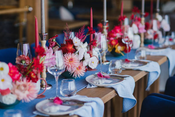 istock Table setting at the wedding reception. Floral compositions with beautiful flowers and greenery, candles, laying and plates on decorated table. 1452173948