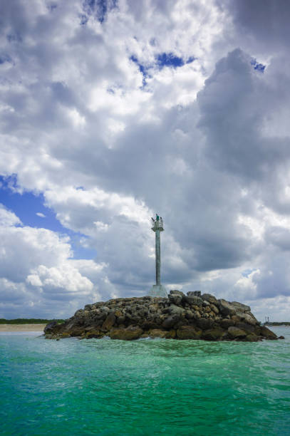 istock Ligth beacon on a rocks mound in beach and big clouds in the background 1452187332