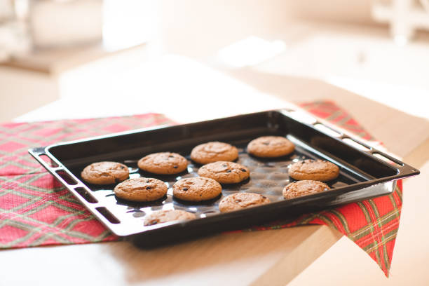 Tasty baked biscuits on baking metal tray on kitchen tray with cloth at home close up. Winter holiday season.