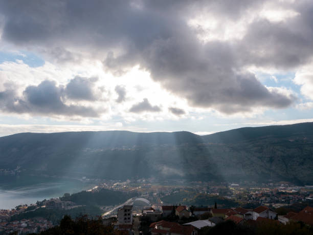 rayons du soleil des nuages sur les toits de tuiles rouges de la ville entourés de montagnes et de la mer vue de fond de la hauteur - apparently photos et images de collection