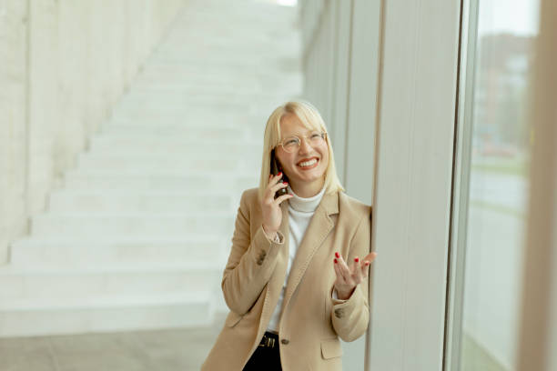 istock Businesswoman using mobile phone on modern office hallway 1452197437