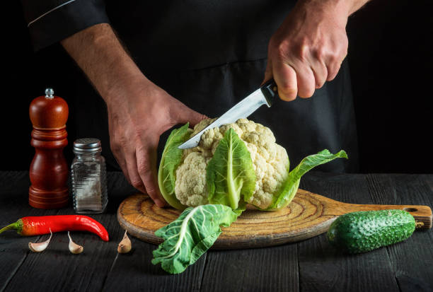 o chef está cortando couve-flor em uma cozinha de restaurante. a ideia de uma deliciosa dieta para o café da manhã ou jantar. - hotel commercial kitchen organic salad - fotografias e filmes do acervo