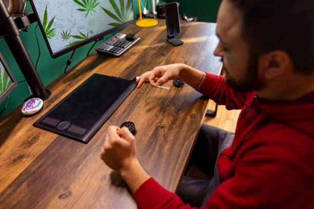 istock Graphic designer making a marijuana joint at the office. Herbal medicine concept. 1452219043