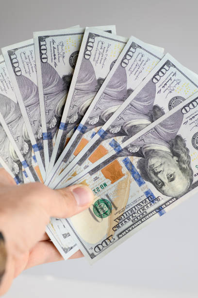 istock Hand holding hundred dollar bills on a white background. 1452232613