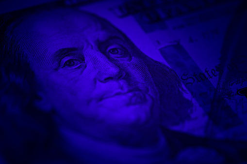 Close up shot of Benjamin Franklin on hundred dollar bill with vignette and blue color