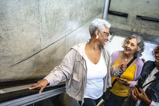 Senior friends talking while go up the escalator in a subway