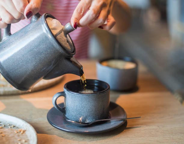 istock a girl pours tea from a teapot into a cup at a table in a cafe, 1452240944