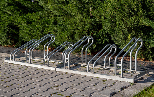 Image of empty bicycle parking rack in front of a row of hedges.