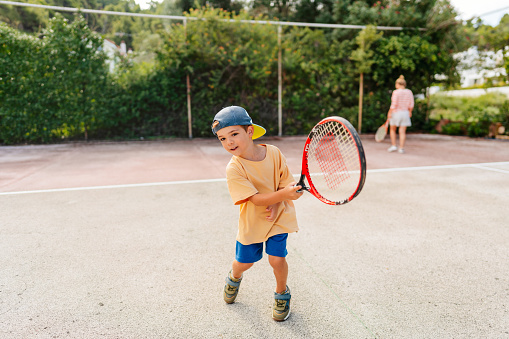 Photo of a little boy practicing tennis