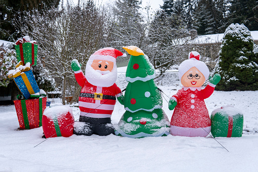 Inflatable figures of Santa Claus, Christmas tree, Santa's wife and boxes with gifts in the snow.  Christmas and New Year holiday outdoor decorations. Snowy winter