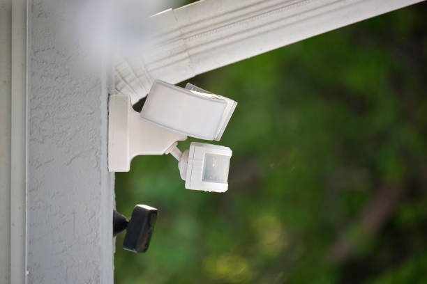 Motion sensor with light detector mounted on exterior wall of private house as part of security system