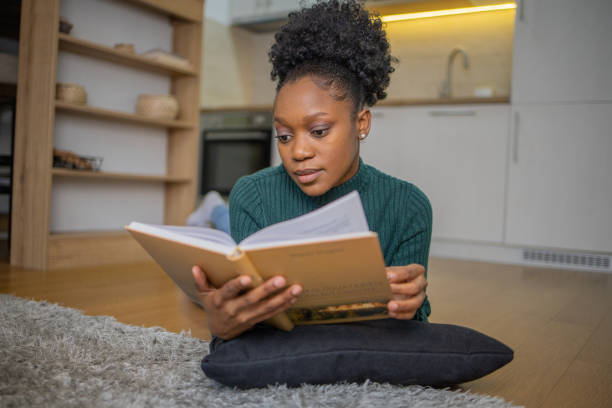 istock Happy woman reading book at home 1452262413
