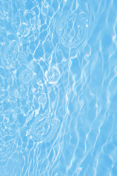 istock Defocus blurred transparent blue colored clear calm water surface texture with splashes and bubbles. Trendy abstract nature background. Water waves in sunlight with caustics. Blue water shinning 1452263312