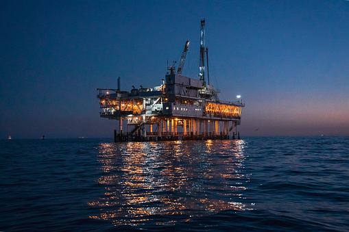 Night Time Offshore Oil Rig Drilling and Fracking Operation, Brightly Lit, on Calm Seas, Oil Platform at Dusk Near Los Angeles, California