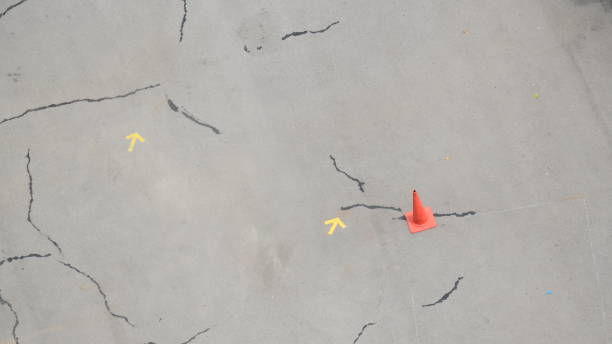 istock cracked road textured background with arrow and cones 1452284917