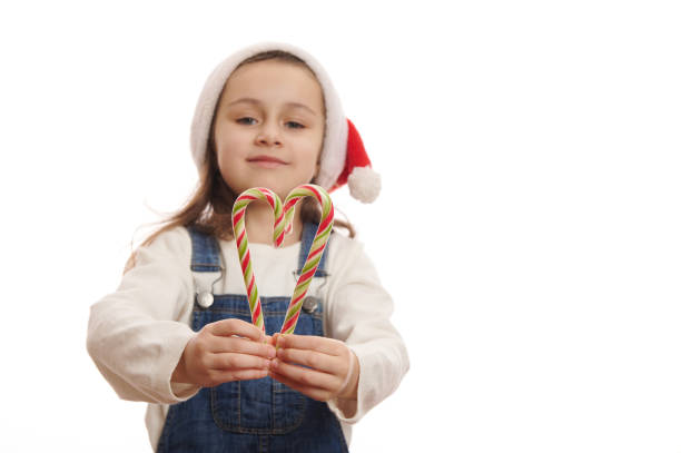 istock Selective focus on green and red stripped lollipops - candy canes in child's hands, isolated over white background 1452289415