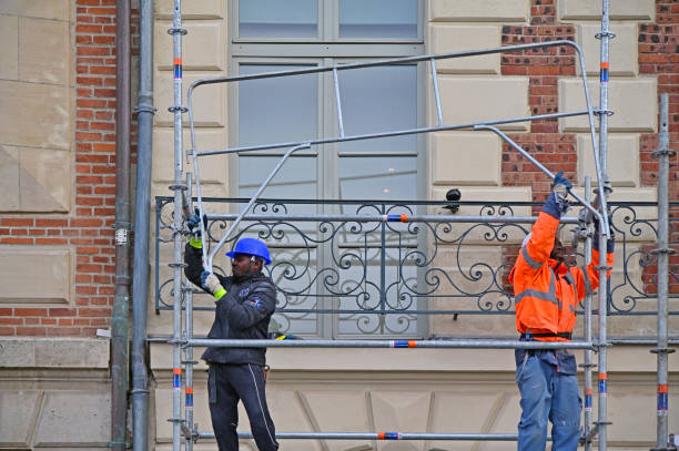 African manual laborers assembling a scaffold beside a building in Paris France stock photo