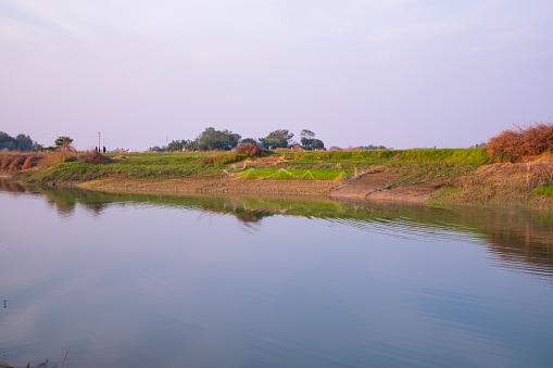 Canal with green grass and vegetation reflected in the water nearby Padma river in Bangladesh