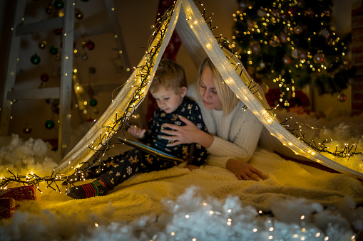 Mother playing under blanket tent with her young son, it's Christmas and they enjoy in time together