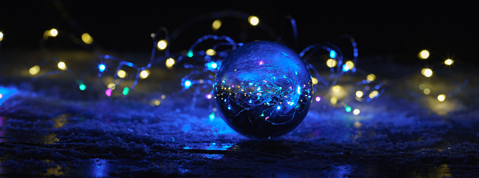 Photography of clear transparent  crystal ball in cold blue light on the snow. The great ball like a world around. Beautiful party inside of ball. Miracle view concept. Close up photography. Panoramic