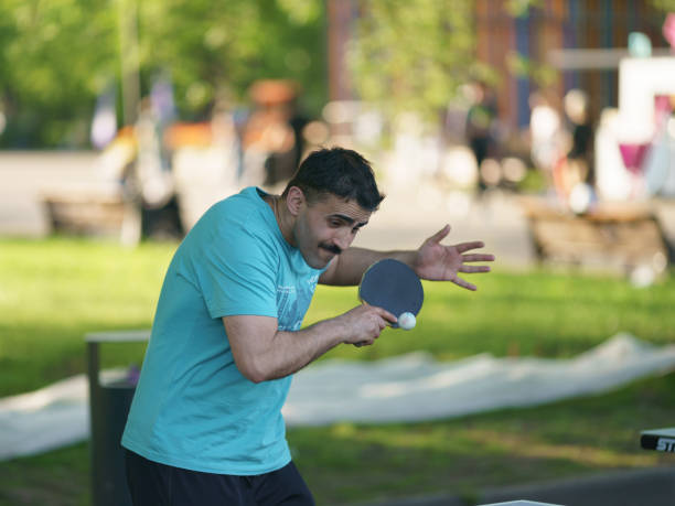 Man playing table tennis in the public park in summer day stock photo