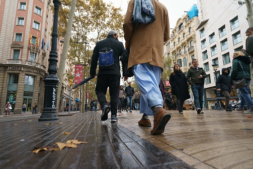 Barcelona, Spain - November 26, 2018: Rambla is full of people. People walk. The city is beautiful despite the autumn rainy day.