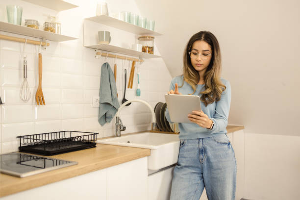 istock Beautiful girl using digital tablet at her kitchen 1452312893