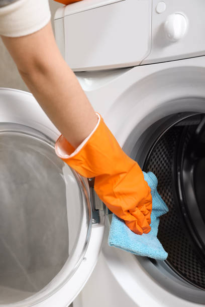 istock Woman cleaning washing machine with rag, closeup 1452319310