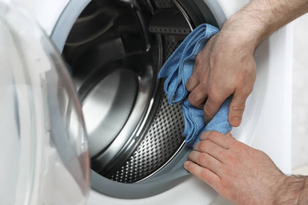 istock Man cleaning empty washing machine with rag, closeup 1452319570