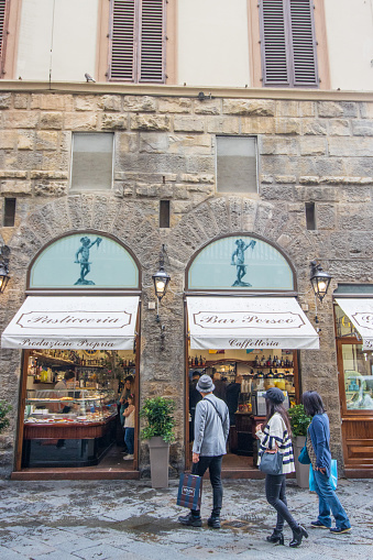 Bakery in Florence at Tuscany, Italy with people visible inside and out, and an image of the Head of Medusa being held up by Perseus.