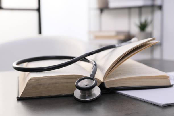 istock Open student textbook and stethoscope on grey table indoors, closeup. Medical education 1452320200