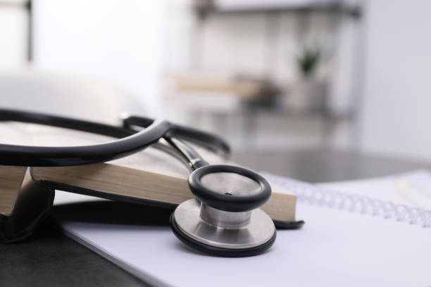 istock Open student textbook and stethoscope on grey table indoors, closeup. Medical education 1452320506