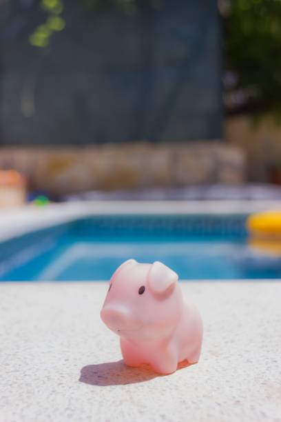 istock Vertical shot of a pink piglet toy on a ledge over a pool 1452321179