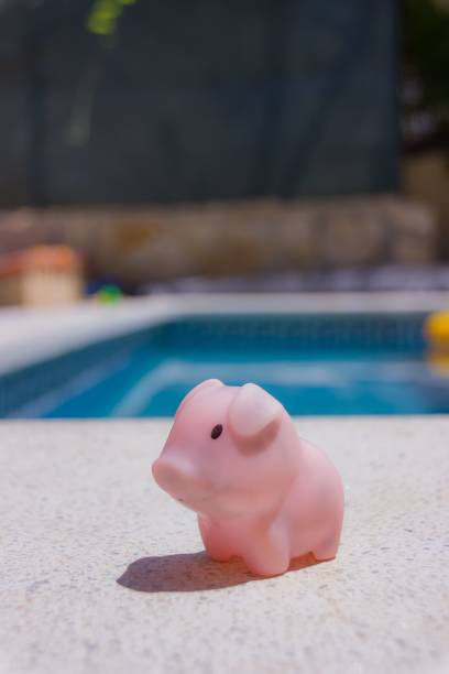 istock Vertical shot of a pink piglet toy on a ledge over a pool 1452321180