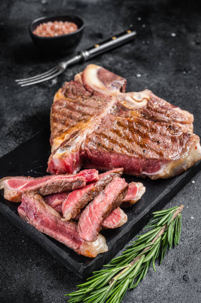 istock T bone grilled beef meat Steak, cooked Porterhouse on a marble board. Black background. Top view 1452323285