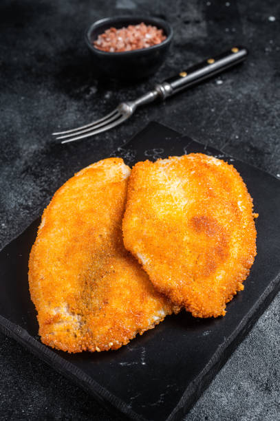 istock Fried breaded tilapia fillets on a marble board. Black background. Top view 1452324920
