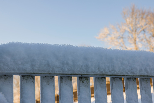 Close up view of white wooden fence covered with snow in winter day. Sweden.