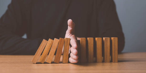 istock Problem Solving,Close up view on hand of business woman stopping falling blocks on table for concept about taking responsibility. 1452334093