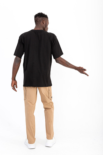 Black male model of African descent in front of white background wearing black t-shirt.