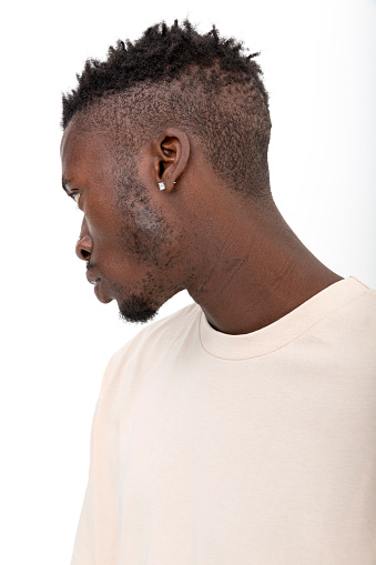 Black male model of African descent in front of white background wearing yellow t-shirt.
