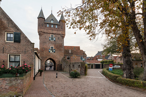 Narrow cobbled street with the historic 14th century city gate of the small Dutch town of Hattem in Gelderland.