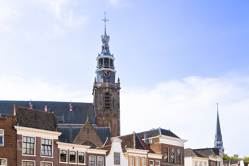 Sint Janskerk with bell tower and facades of city buildings on the market square in the picturesque cheese town of Gouda.