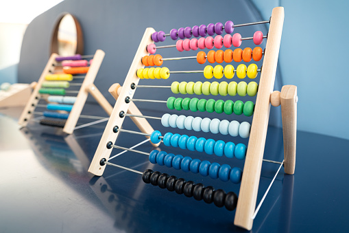 A colorful abacus on wooden table at kid zone in preschool play room. Education and toy object photo, selective focus.