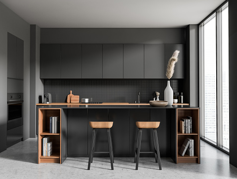 Front view on dark kitchen room interior with panoramic window, island with barstools, books, grey wall, concrete floor, sink, gas cooker, crockery. Concept of minimalist design. 3d rendering