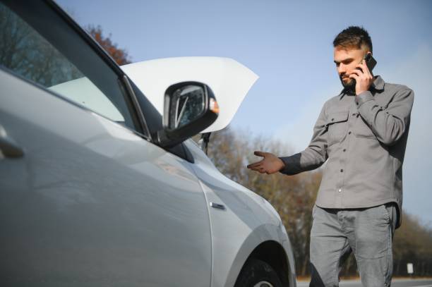 istock Sad driver calling car service, opening hood, having engine problem standing near broken car on the road. Car breakdown concept 1452337555