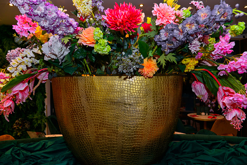 Bouquet of artificial diverse flowers Close-up in a beautiful golden vase